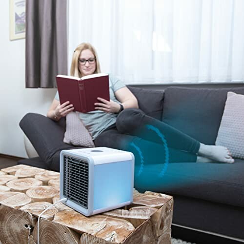 Frau liest auf dem Sofa neben einem Luftkühler.